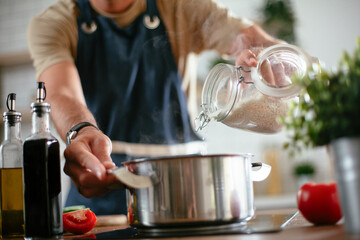 Handsome man preparing pasta in the kitchen. Close up of guy cooking a tasty meal.