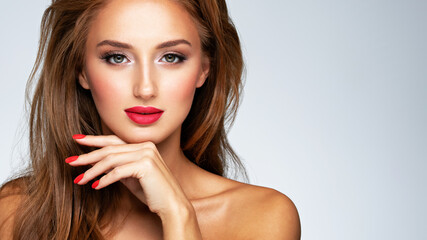 Face of young woman with red nails, lipstick and long brown hair.   Model with fashion makeup.