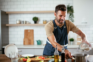 Handsome man preparing pasta in the kitchen. Guy cooking a tasty meal.