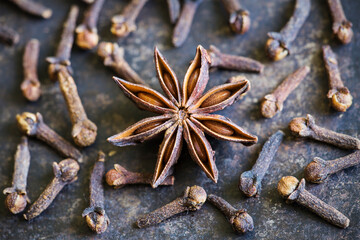 Star anise with cloves in the kitchen. Thanksgiving or christmas cooking, aromatic spices background.
