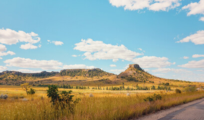 Fototapeta premium Low grass growing on African savanna, small rocky mountains in background - typical scenery at Isalo national Park, Madagascar