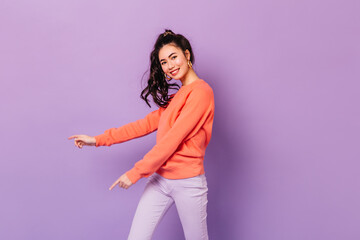 Excited asian girl in casual outfit smiling at camera. Studio shot of pretty japanese young woman isolated on purple background.