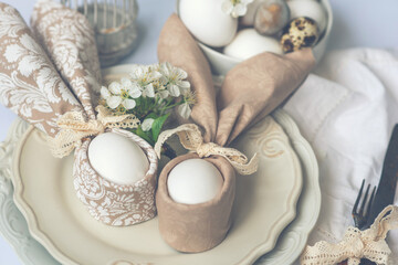 Arrangement decoration Happy Easter holiday background concept. Bunny eggs with spring flowers on vintage beautiful plate. Pastel tone. Beautiful festive Easter table setting with napkin Easter Bunny.