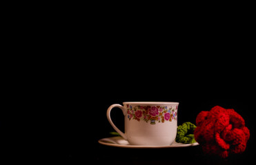 cup of coffee on a black background with a knitted, crocheted red rose. for message, for mom. Mother's day.