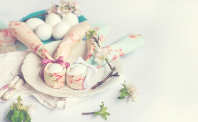 Easter background with Easter eggs and spring flowers. Easter eggs cute bunny on a white plate. Festive decoration. Happy Easter! Copy space for you text. Toned image.