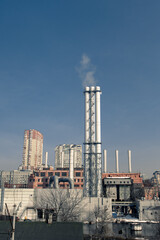 Obraz premium Combined heat and power plant. Smoke from the chimneys of a large factory. Large steam pipes of a working plant
