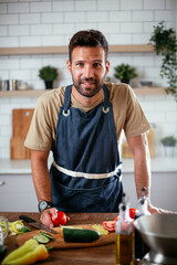 Handsome man preparing vegetable salad in the kitchen. Healthy Food. Vegan Salad.