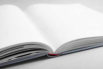 Open book with hard cover on light grey table, closeup