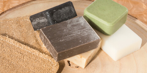Solid shampoo soap conditioner bar, natural body care eco friendly products and loofah sponges on wooden board and beige neutral paper