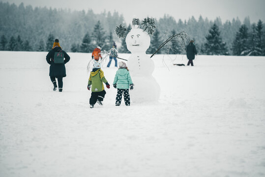 Schneemann in Winterlandschaft mit spielenden Kindern