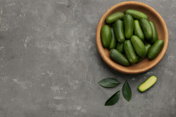 Wooden bowl with seedless avocados on grey table, flat lay. Space for text