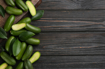 Fresh seedless avocados with green leaves on wooden table, flat lay. Space for text