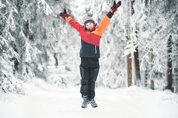 Kind springt in die Luft im Schnee im Winter