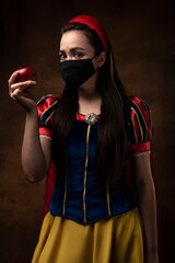 A girl in a princess costume wearing a protective mask. Prohibition. Red apple. A pandemic. Coronavirus.