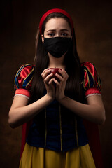 A girl in a princess costume wearing a protective mask. Prohibition. Red apple. A pandemic. Coronavirus.