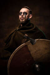 A medieval Viking warrior with war paint, beard, and shield. The concept of historical photography.