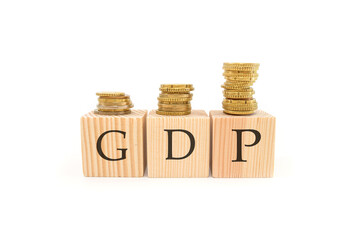 The word GDP. gross domestic product on wooden blocks and stacks of coins.