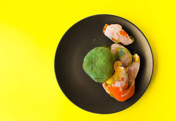Spoiled fruits on a black plate on a yellow background