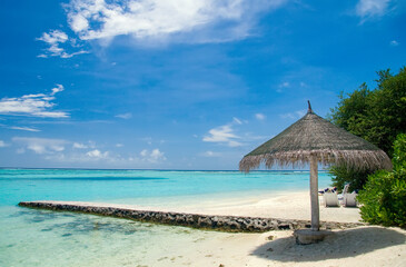 Tropical island in the Indian Ocean, Maldives. Beautiful tropical beach with breakwater and parasol