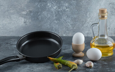 Fresh organic eggs with pepper and oil on grey background