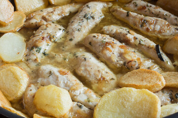 Recipe of chicken fillets with garlic and spices in a green sauce accompanied by baked potatoes. Homemade food.