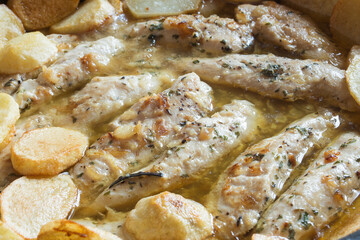 Close-up of chicken fillets with garlic and spices in a green sauce accompanied by baked potatoes. Healthy food.