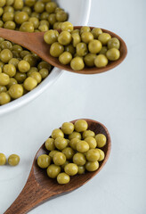 Two wooden spoon and ceramic bowl full with green marinated olives