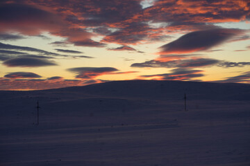 mountains of snow on the background of the rising sun and clouds