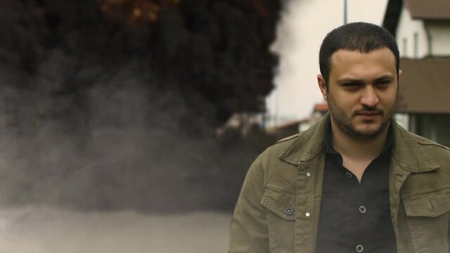 cool guy walks in the background of a car explosion