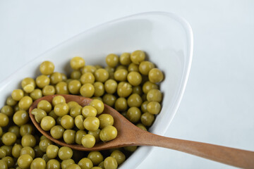 Close up photo of marinated green olive in white bowl with wooden spoon