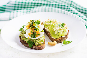 Vegetarian breakfast. Sandwich with avocado puree, boiled eggs and sandwich cream cheese, kiwi, nuts.  Healthy breakfast or lunch.