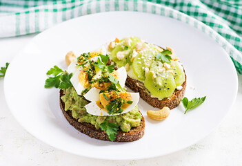 Vegetarian breakfast. Sandwich with avocado puree, boiled eggs and sandwich cream cheese, kiwi, nuts.  Healthy breakfast or lunch.