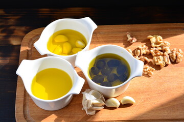 garlic in olive oil. black olive in oil. with herb rosemary walnuts on a wooden board