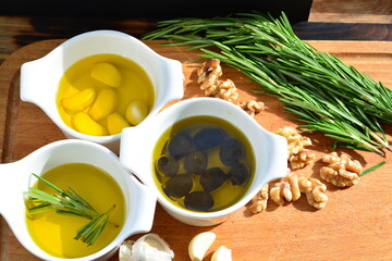 garlic in olive oil. black olive in oil. with herb rosemary walnuts on a wooden board