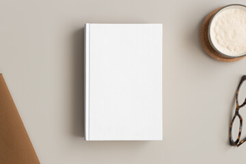 White book mockup with a coffee and workspace accessories on the beige table.