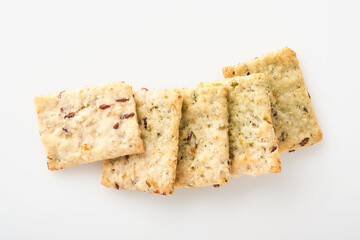 Stack of grain salty crackers with bran and flax seeds on white background. Top view.