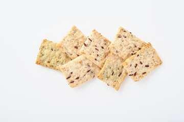 Stack of grain salty crackers with bran and flax seeds on white background. Top view.