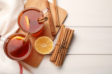 Delicious hot tea with cinnamon and lemon on white wooden table, flat lay. Space for text