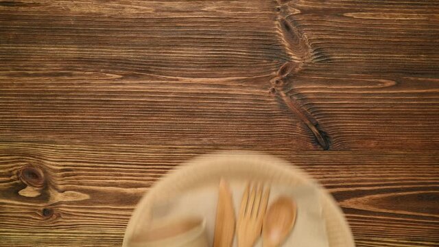 Exchanging plastic plate, cup and cutlery with eco friendly biodegradable paper plate and cup and wooden cutlery.  Top view on wooden table. 