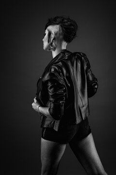 Attractive young woman from back, with punk hairstyle, wearing leather jacket and fishnet stockings