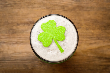 Glass of beer with clover leaf on wooden table, top view. St Patrick's Day celebration