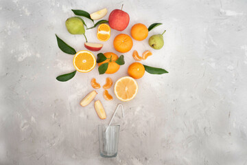 Many different fruits: tangerines, oranges, grapefruits, lemon, apples and pears on grey background. All vitamins fit in one glass. Many vitamins fresh juices are good for healthy lifestyle.