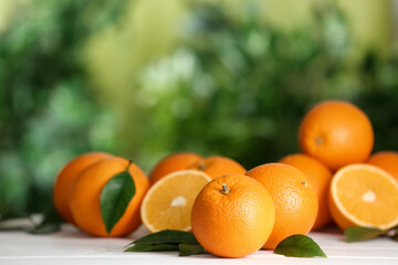 Fototapeta na wymiar Fresh ripe oranges on white table against blurred background. Space for text