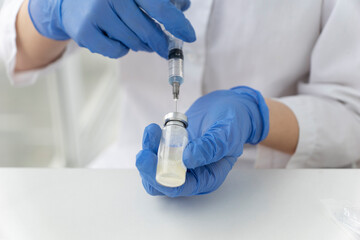 doctors hands hold syringe and vial with vaccine gaining the dose for injection. Healthcare  and vaccination concept.