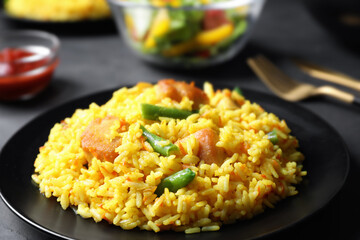 Delicious rice pilaf with meat on black plate, closeup