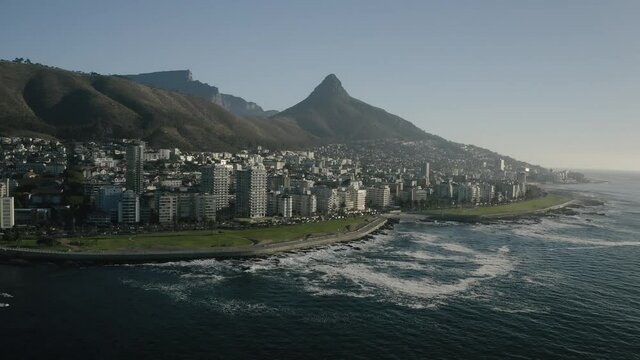 Aerial view of Cape Town, South Africa, with Green Point and Sea Point, Table Mountain, Lion's Head, Signal Hill and Devil's Peak on a bright and sunny day filmed in 4k with a drone