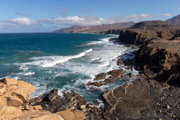 Fototapeta na wymiar Ocean view on la Pared beach. Beautiful view of the clear sea, waves, cliffs and beach in Playa de la Pared - Canary Islands, Fuerteventura, Spain. 