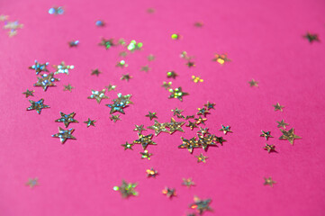 Shiny stars on a bright pink background. Festive background. Flat lay.