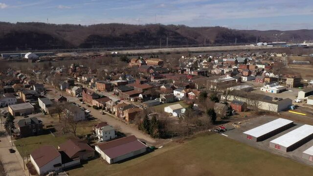 A slow forward aerial establishing shot of a typical Pennsylvania small town in late winter. Pittsburgh suburbs.  	