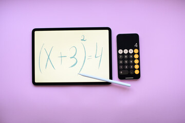 Tablet with the mathematical equation inscription with Pencil and telephone -calculator on pink...